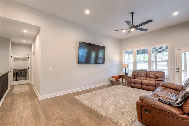 living room featuring washing machine and clothes dryer, wood-type flooring, and ceiling fan