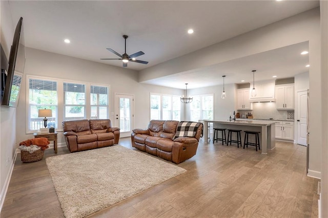 living room with ceiling fan, sink, and light hardwood / wood-style floors