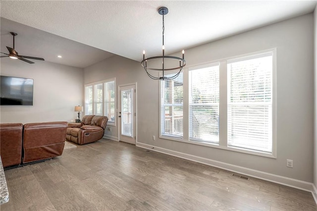 interior space featuring ceiling fan with notable chandelier, a textured ceiling, and hardwood / wood-style floors