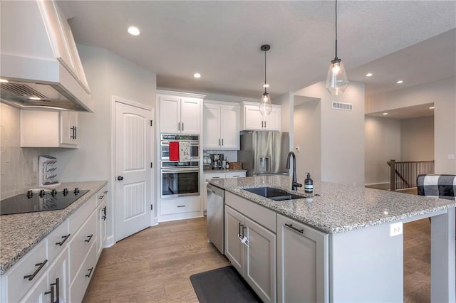 kitchen with appliances with stainless steel finishes, light hardwood / wood-style floors, white cabinetry, custom exhaust hood, and sink