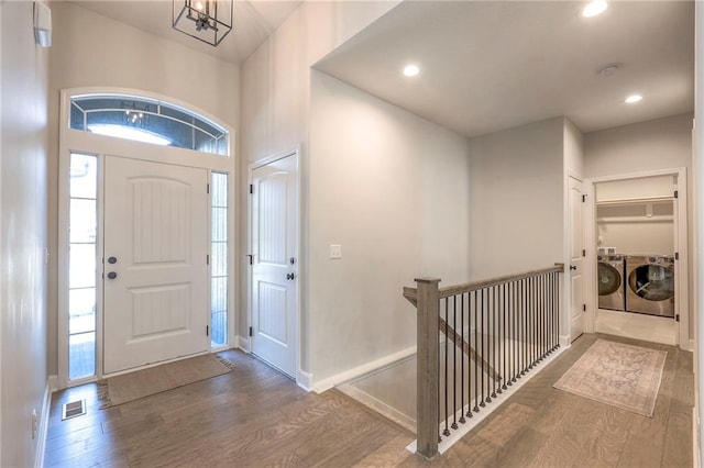 entryway featuring wood-type flooring, independent washer and dryer, and a notable chandelier