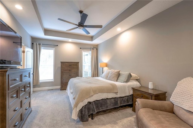 carpeted bedroom featuring a tray ceiling and ceiling fan