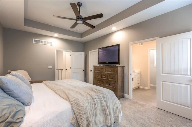 carpeted bedroom featuring a tray ceiling, ceiling fan, and ensuite bathroom