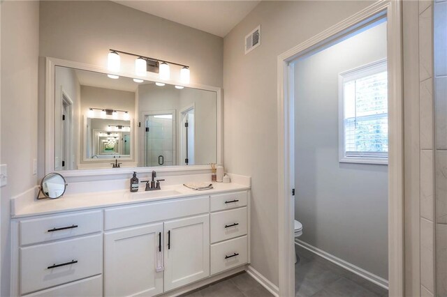 bathroom featuring tile patterned flooring, vanity, toilet, and a shower with door