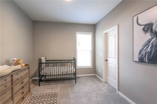 bedroom featuring light colored carpet and a nursery area