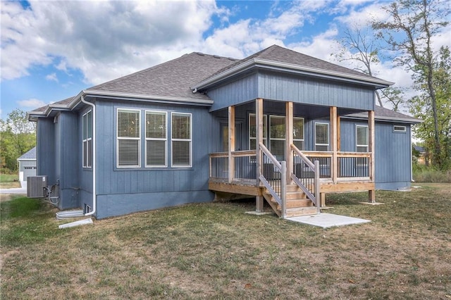 rear view of property featuring a lawn and central air condition unit