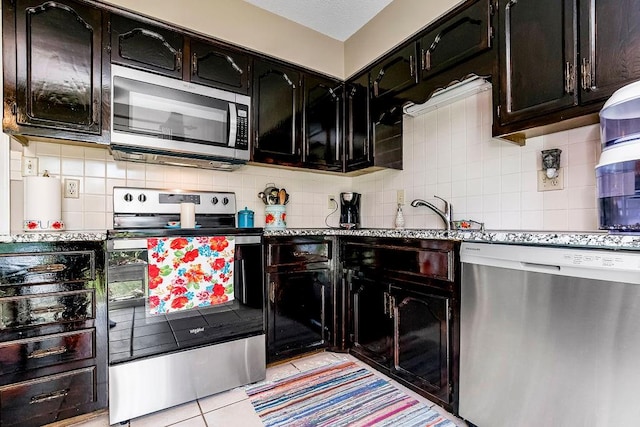 kitchen with light tile patterned floors, stainless steel appliances, decorative backsplash, and stone countertops