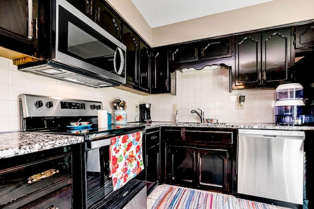 kitchen with light stone counters, appliances with stainless steel finishes, and decorative backsplash