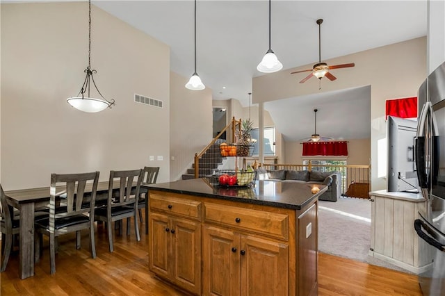 kitchen with pendant lighting, ceiling fan, a center island, and light wood-type flooring