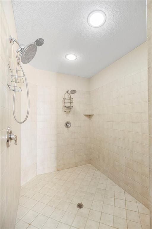 bathroom featuring tile patterned floors, a tile shower, and a textured ceiling