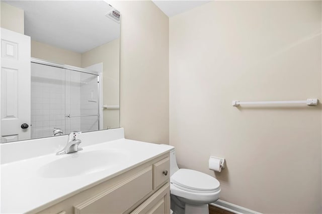 bathroom featuring vanity, toilet, and a shower with door