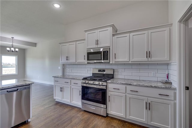 kitchen with backsplash, white cabinets, dark wood-type flooring, and appliances with stainless steel finishes