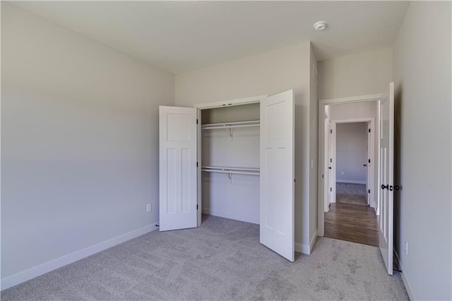 unfurnished bedroom featuring light carpet and a closet