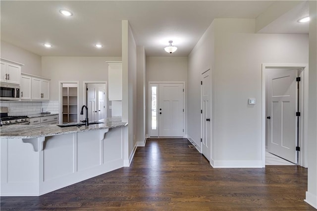 kitchen featuring dark wood-type flooring, sink, light stone countertops, white cabinetry, and stainless steel appliances