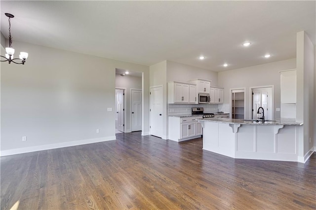 kitchen featuring kitchen peninsula, dark hardwood / wood-style floors, appliances with stainless steel finishes, a kitchen bar, and white cabinetry