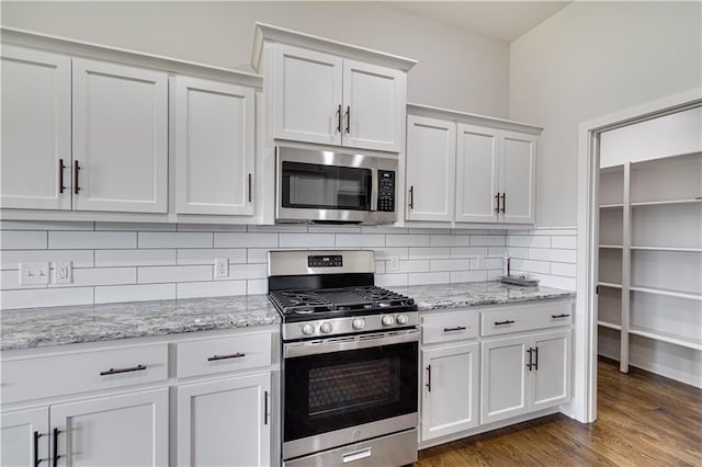 kitchen with decorative backsplash, appliances with stainless steel finishes, white cabinetry, and dark wood-type flooring