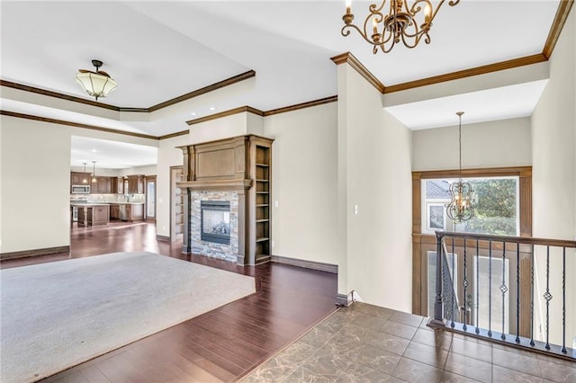 unfurnished living room featuring a notable chandelier, dark hardwood / wood-style floors, a fireplace, and crown molding