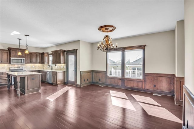 kitchen featuring appliances with stainless steel finishes, dark hardwood / wood-style floors, hanging light fixtures, and a kitchen island