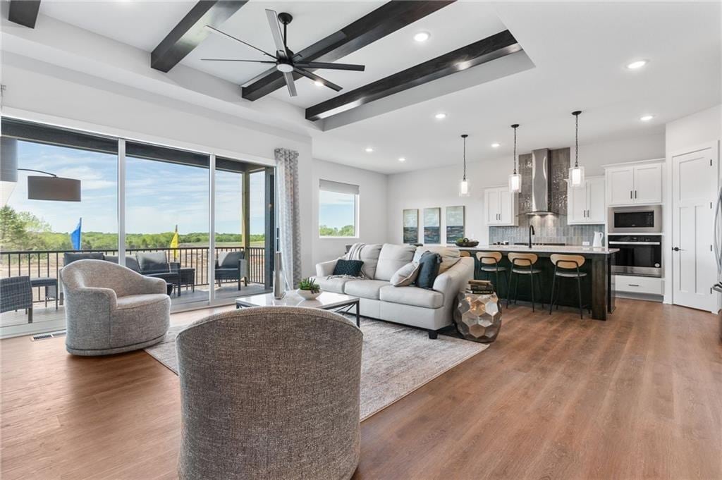 living area featuring beamed ceiling, recessed lighting, ceiling fan, and wood finished floors