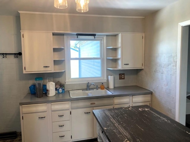 kitchen featuring backsplash, ornamental molding, sink, and white cabinets