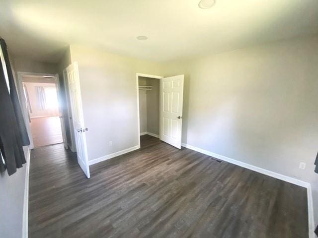 unfurnished bedroom featuring a closet and dark wood-type flooring