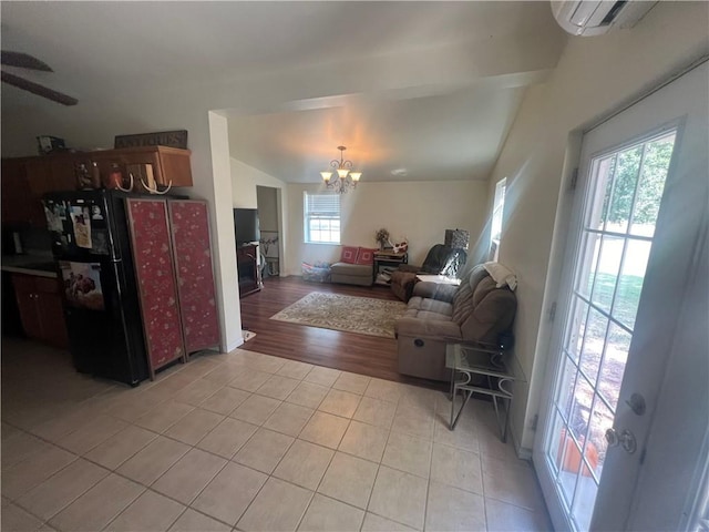 living room with light wood-type flooring, ceiling fan with notable chandelier, lofted ceiling, and a wall unit AC