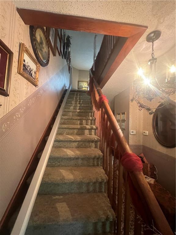 stairway featuring a textured ceiling