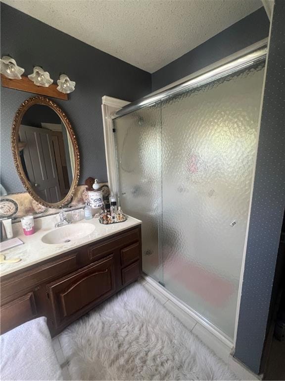 bathroom featuring a textured ceiling, vanity, and a shower with shower door