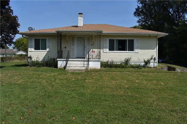 view of front facade with a front yard, a porch, and a chimney