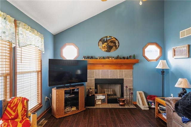 living room featuring lofted ceiling, a tiled fireplace, and dark wood-type flooring