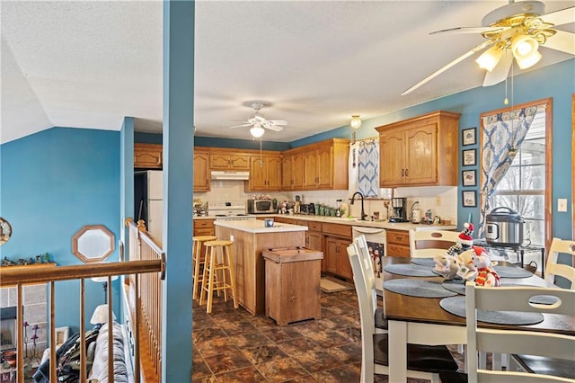 kitchen with sink, a kitchen bar, a kitchen island, decorative backsplash, and ceiling fan