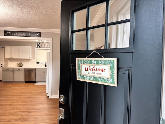 room details featuring a textured ceiling, stainless steel dishwasher, hardwood / wood-style floors, and white fridge