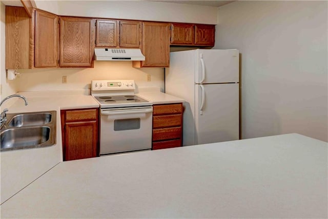 kitchen with white appliances, brown cabinetry, light countertops, under cabinet range hood, and a sink