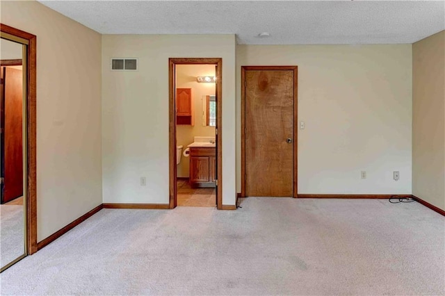 spare room featuring baseboards, visible vents, a textured ceiling, and light colored carpet