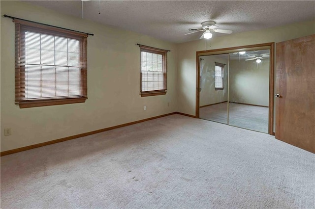 unfurnished bedroom with a closet, light carpet, a textured ceiling, and baseboards