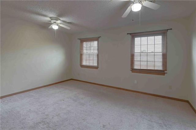 carpeted empty room featuring ceiling fan, a textured ceiling, and baseboards