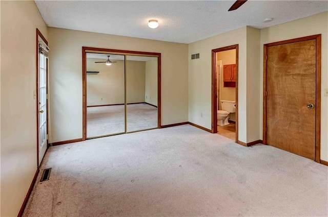 unfurnished bedroom featuring light colored carpet, visible vents, connected bathroom, and baseboards