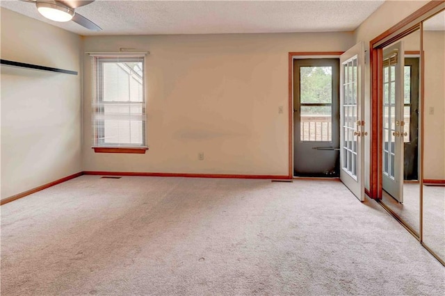 empty room featuring a healthy amount of sunlight, a textured ceiling, and light colored carpet