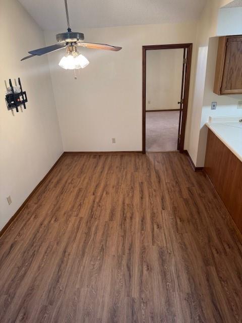 interior space featuring vaulted ceiling, ceiling fan, dark wood finished floors, and baseboards