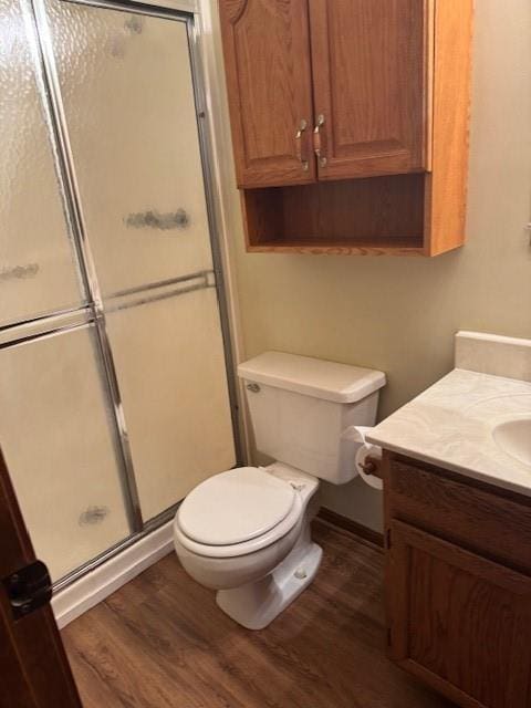 bathroom with toilet, a shower stall, vanity, and wood finished floors