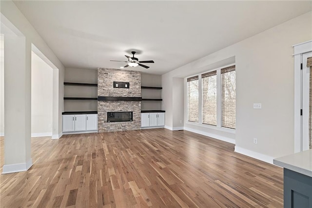 unfurnished living room featuring ceiling fan, a fireplace, and light hardwood / wood-style flooring