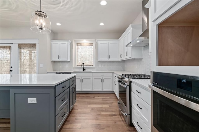 kitchen featuring gray cabinetry, white cabinetry, sink, wall chimney exhaust hood, and stainless steel appliances