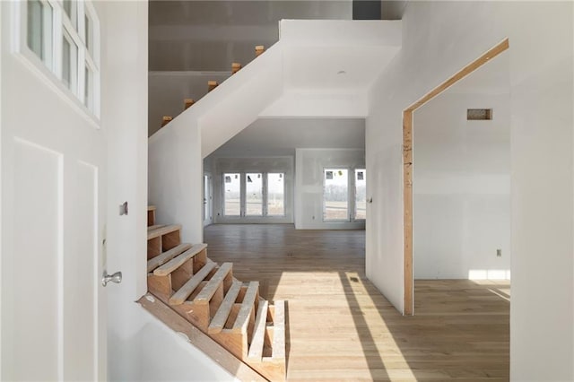 staircase featuring a towering ceiling and hardwood / wood-style flooring