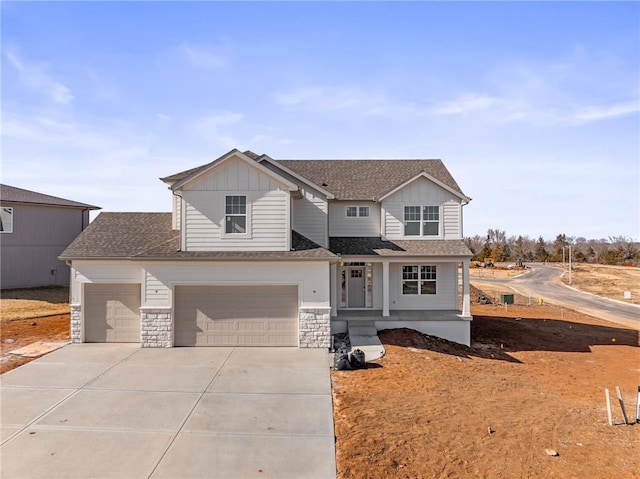 view of front of house with stone siding, board and batten siding, concrete driveway, and a shingled roof