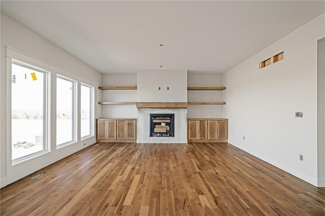 unfurnished living room featuring baseboards, wood finished floors, and a fireplace