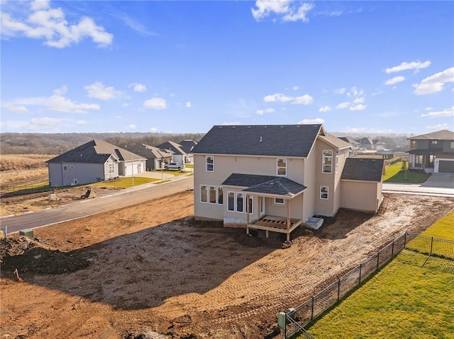 back of property featuring a residential view, a shingled roof, and fence