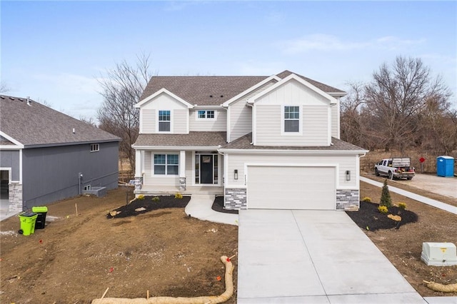 traditional home featuring stone siding, an attached garage, driveway, and a shingled roof