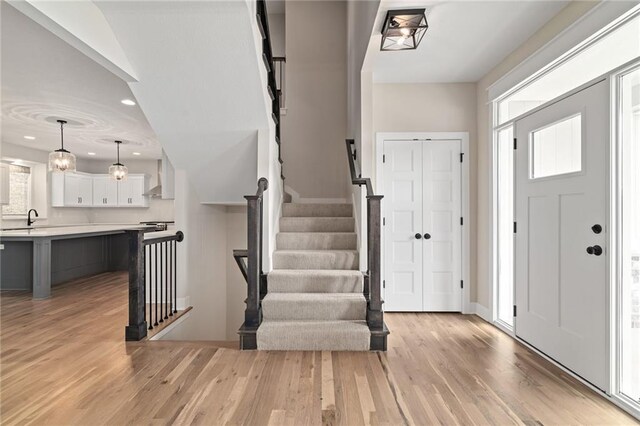 entryway with a wealth of natural light, light wood-style flooring, and stairs