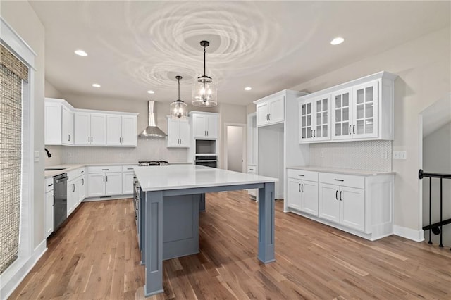 kitchen with oven, dishwasher, light wood-type flooring, white cabinets, and wall chimney exhaust hood