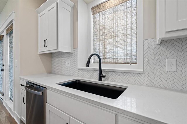 kitchen featuring a sink, backsplash, light countertops, and stainless steel dishwasher